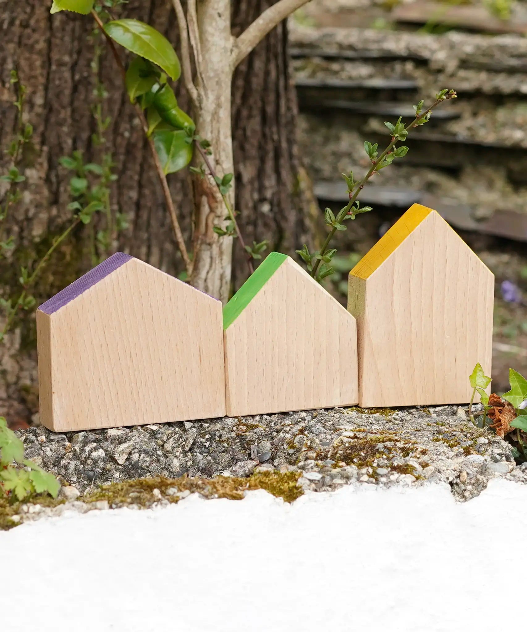 Grapat handcrafted wooden house shaped blocks with coloured roofs on a stone wall