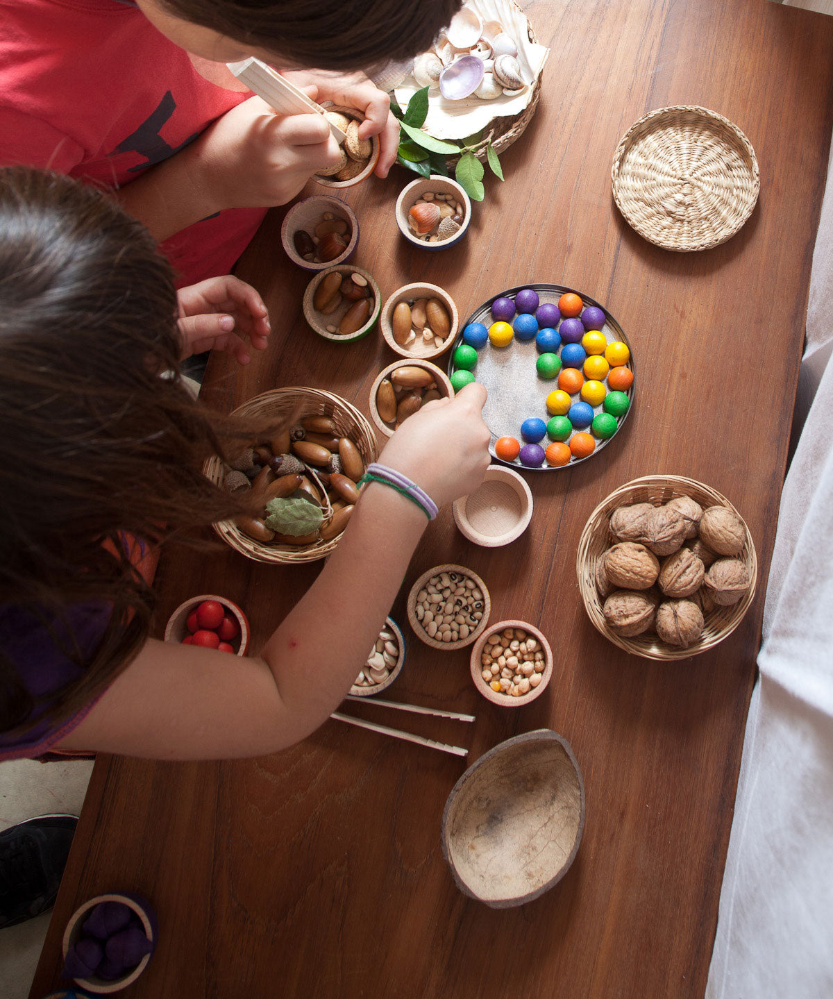 Grapat wooden marbles placed on a tin lid. These wooden toys are part of a wide range of open ended toys available at Babipur.  