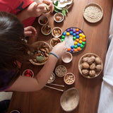 Grapat wooden marbles placed on a tin lid. These wooden toys are part of a wide range of open ended toys available at Babipur.  