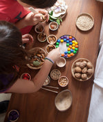 Grapat wooden marbles placed on a tin lid. These wooden toys are part of a wide range of open ended toys available at Babipur.  