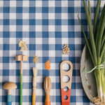 A child is mixing different food items together with the blue and purple handled Grapat Wooden Sensory Play Tools
