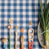 A child is mixing different food items together with the blue and purple handled Grapat Wooden Sensory Play Tools