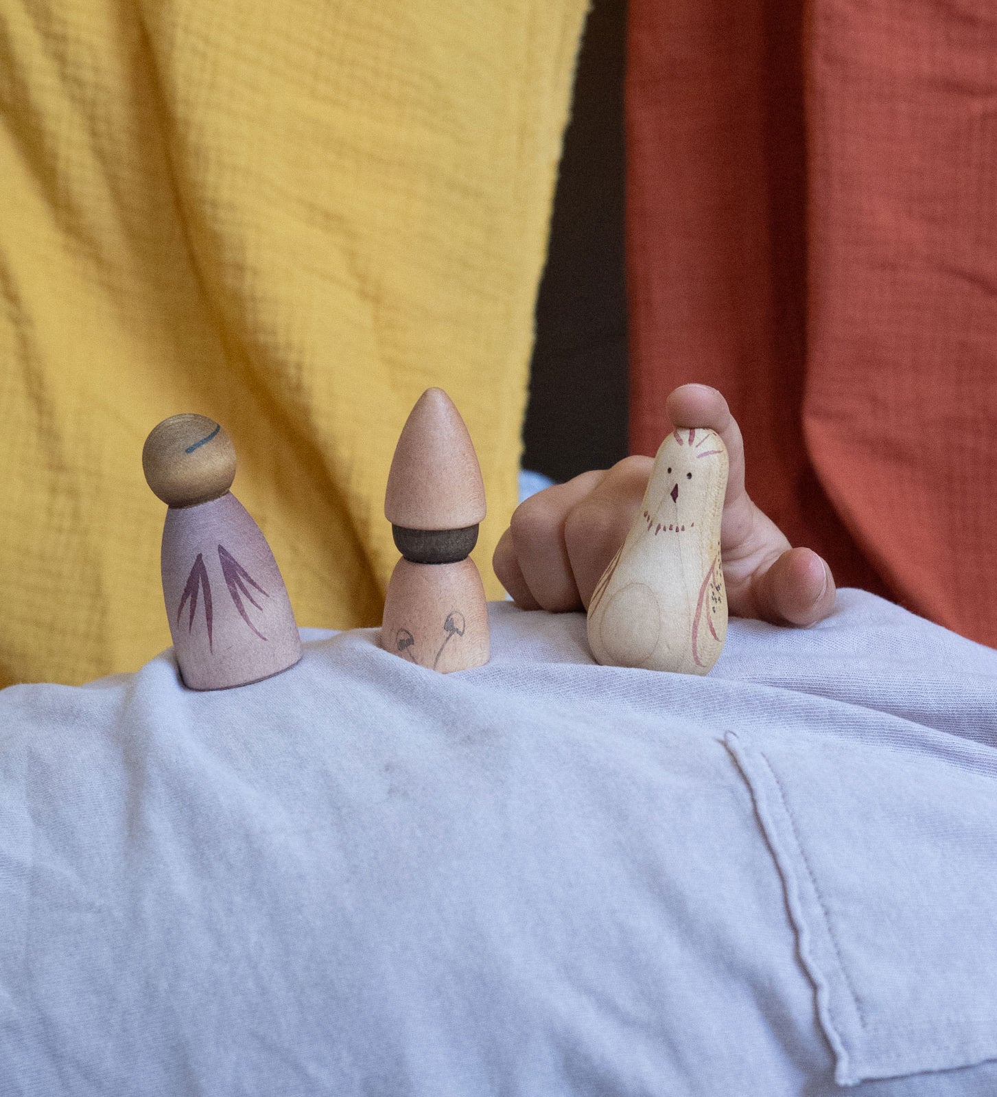 A child playing with three pieces from the Grapat Moonlight Tale Play Set. Various handmade and hand painted wooden figures of mushrooms.