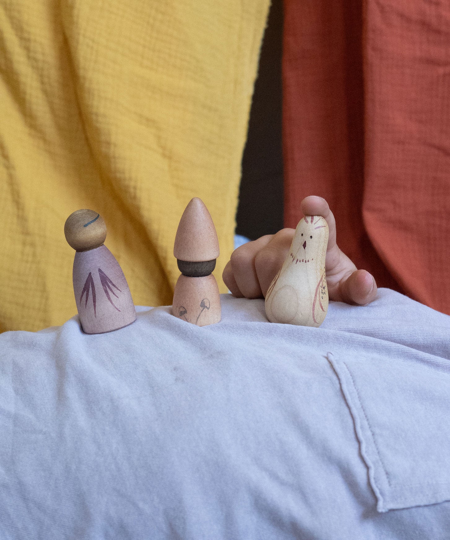 A child playing with three pieces from the Grapat Moonlight Tale Play Set. Various handmade and hand painted wooden figures of mushrooms.