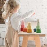 A child playing with the Grapat Nesting Bowls on a wooden table. 