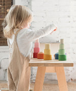 A child playing with the Grapat Nesting Bowls on a wooden table. 
