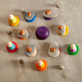 A selection of wooden toys from Grapat including Nins, wooden bowls and rings placed on the floor. Some have stones balanced on them.  