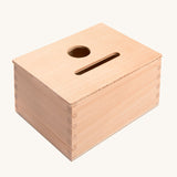 Grapat Permanence Box. A wooden box that has two slots in the top one for coins and one circular that will fit small toys such as Nin peg dolls. This wooden box is part of a wide range of open ended toys available at Babipur. 