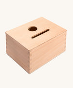 Grapat Permanence Box. A wooden box that has two slots in the top one for coins and one circular that will fit small toys such as Nin peg dolls. This wooden box is part of a wide range of open ended toys available at Babipur. 