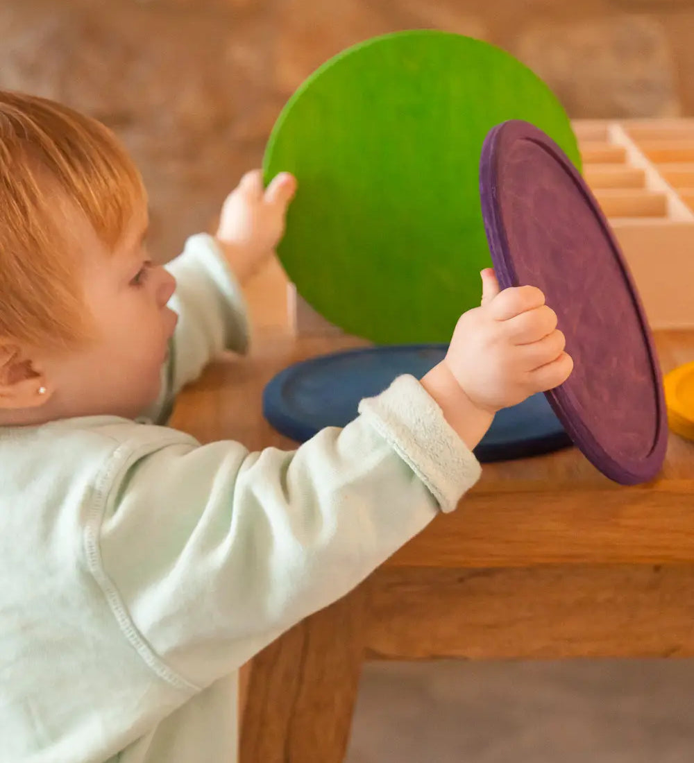 A child holding a green and purple Grapat handcrafted wooden dishes