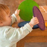 A child holding a green and purple Grapat handcrafted wooden dishes