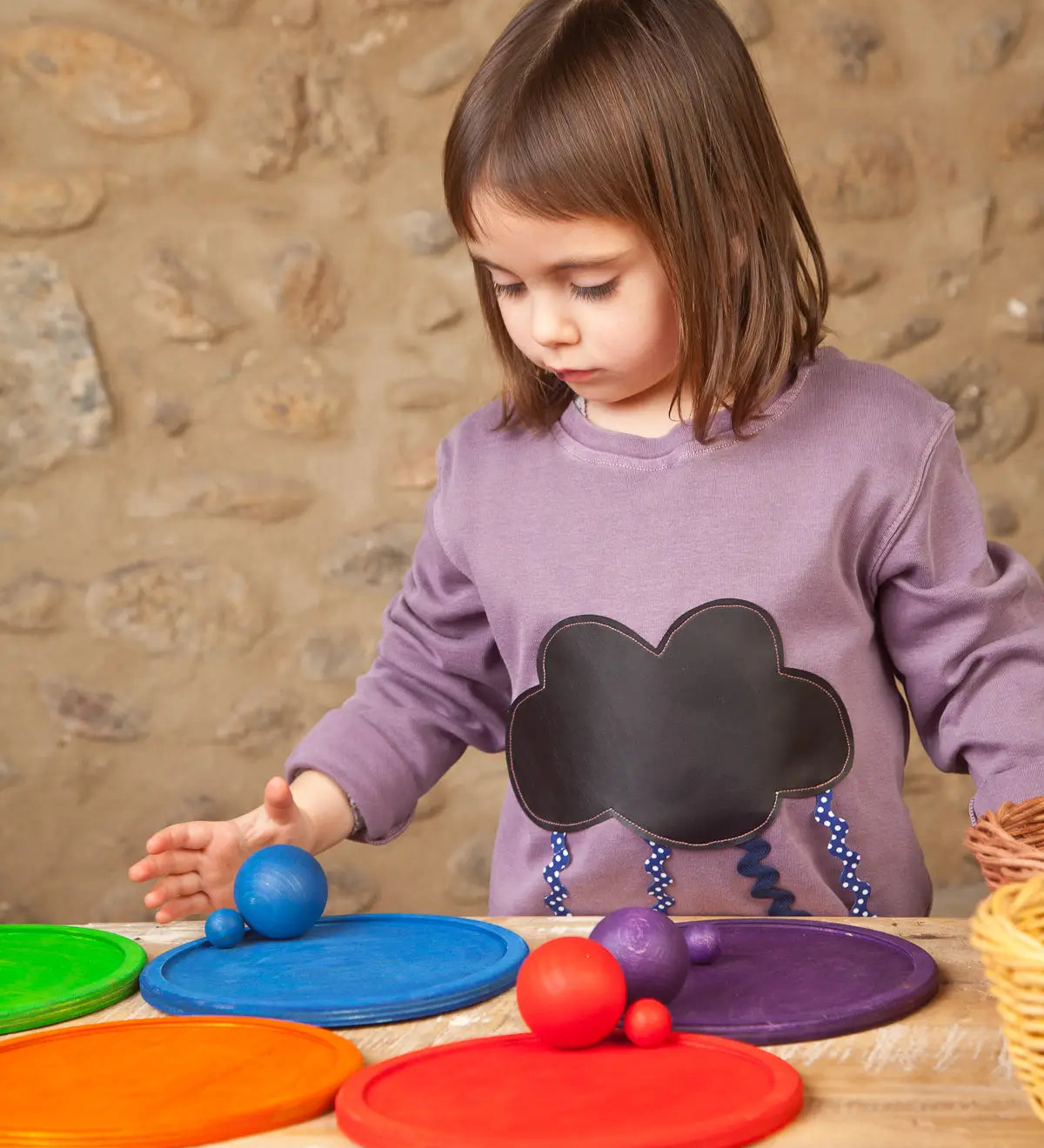 Child playing a sorting game using Grapat's handcrafted wooden rainbow dish pieces and matching balls