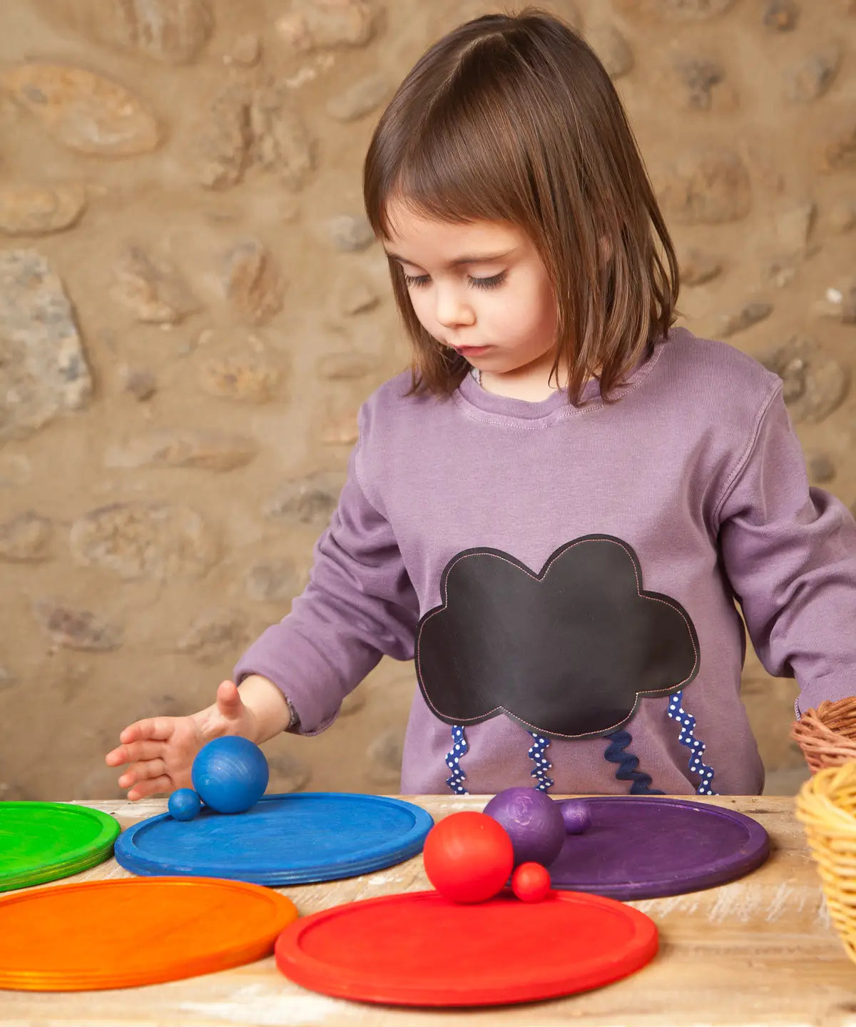 Child playing a sorting game using Grapat's handcrafted wooden rainbow dish pieces and matching balls