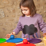 Child playing a sorting game using Grapat's handcrafted wooden rainbow dish pieces and matching balls