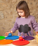 Child playing a sorting game using Grapat's handcrafted wooden rainbow dish pieces and matching balls