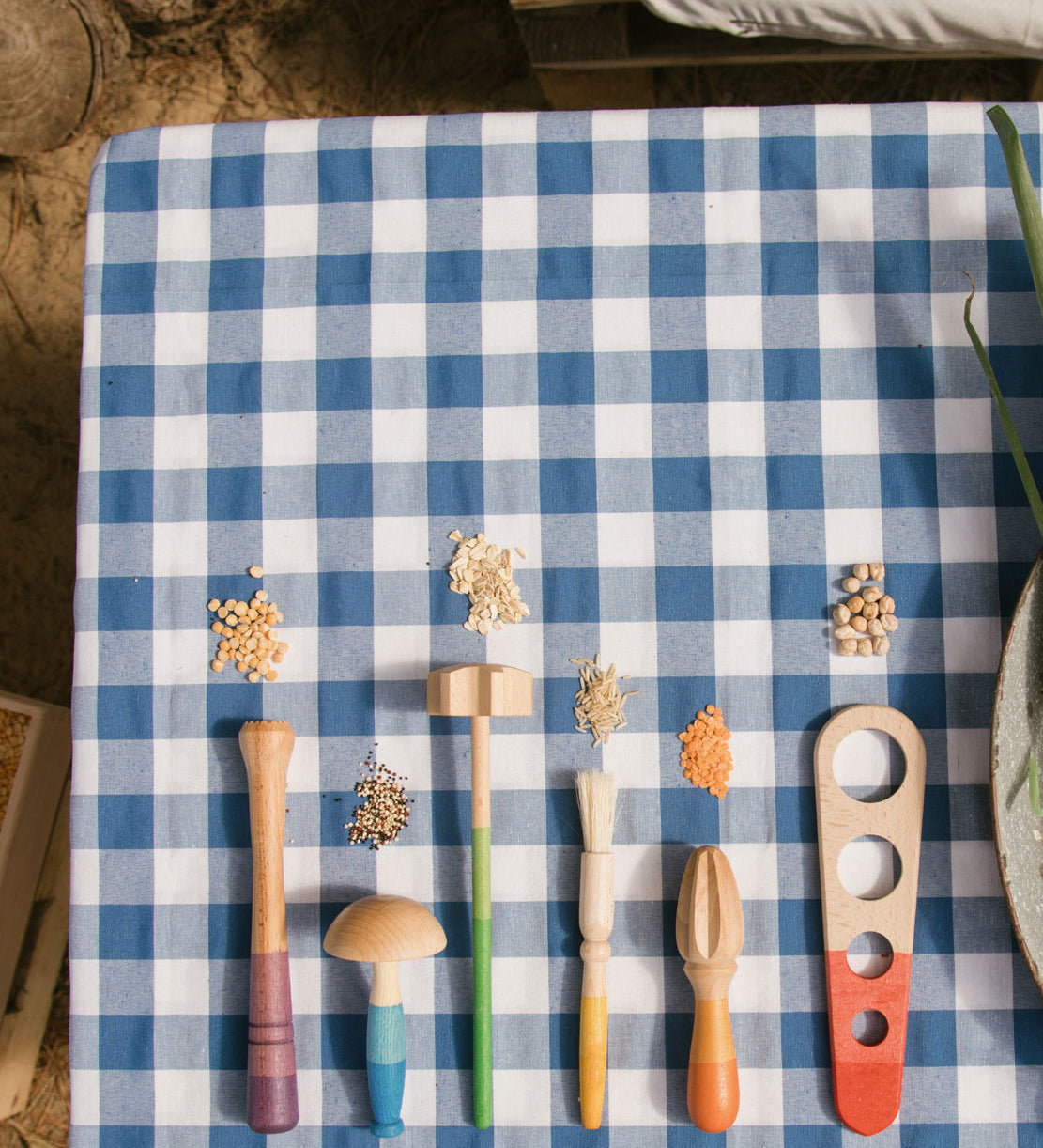 Grapat Sensory Play Tools wooden toy set. The play tools are placed on a blue and white gingham tablecloth.