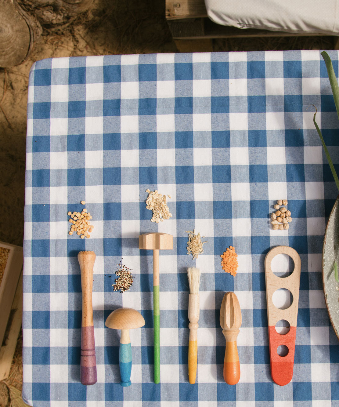 Grapat Sensory Play Tools wooden toy set. The play tools are placed on a blue and white gingham tablecloth.