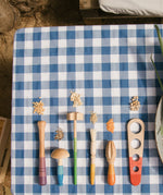Grapat Sensory Play Tools wooden toy set. The play tools are placed on a blue and white gingham tablecloth.