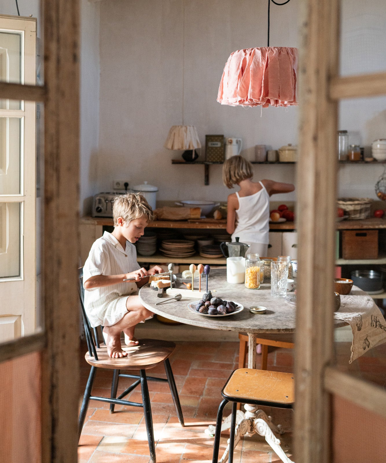 Child sitting next to the kitchen table playing with the Grapat handcrafted wooden puppets with 4 puppets resting on the wooden stand.
