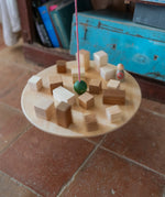Grapat wooden pendulum set with wooden blocks on the balancing on the wooden balance board above a terracotta floor.