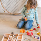 A Grapat tinker tray filled with loose pieces next to a child sorting other wooden pieces 