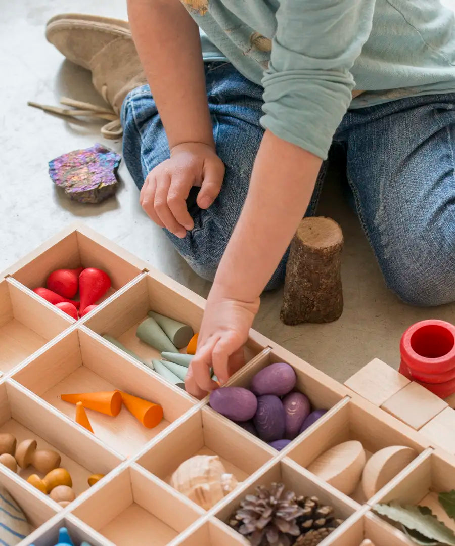 Child sorting different loose pieces in a Grapat wooden tinker tray 