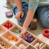 Child sorting different loose pieces in a Grapat wooden tinker tray 