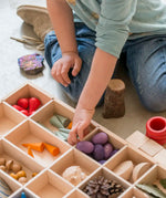 Child sorting different loose pieces in a Grapat wooden tinker tray 