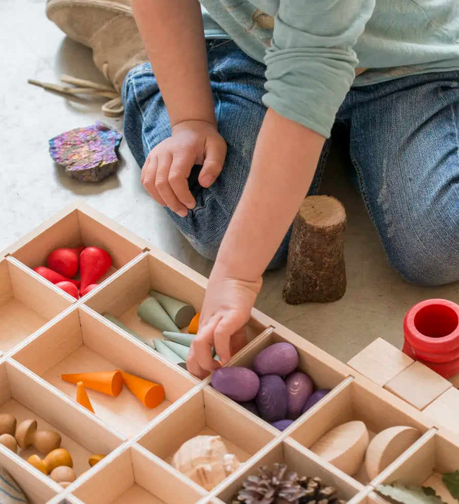 Child sorting different loose pieces in a Grapat wooden tinker tray 