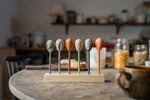 Grapat handcrafted and painted wooden twin soul puppets on a wooden stand next a jar or cereal on a kitchen table. Features a fox, owl, moon, flower, wolf and a bear resting on a wooden stand.