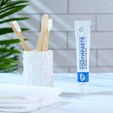 Organic People peppermint and aloe vera toothpaste tube in the bathroom next to a toothbrush holder 