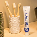 Tube of Organic People peppermint and aloe vera toothpaste next to a toothbrush holder