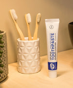 Tube of Organic People peppermint and aloe vera toothpaste next to a toothbrush holder