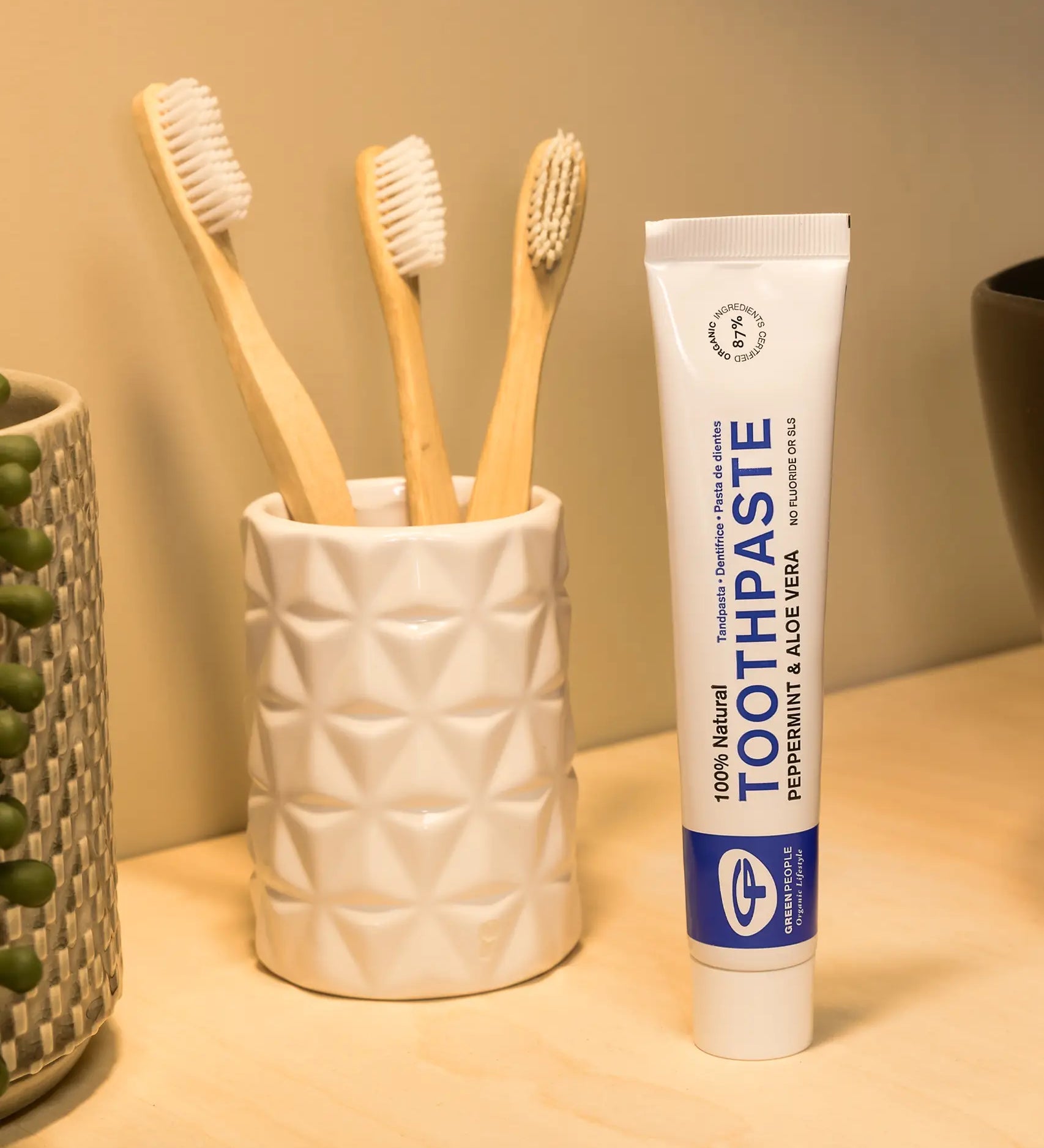 Tube of Organic People peppermint and aloe vera toothpaste next to a toothbrush holder