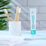 Organic People minty cool toothpaste tube in the bathroom next to a toothbrush holder 