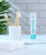 Organic People minty cool toothpaste tube in the bathroom next to a toothbrush holder 
