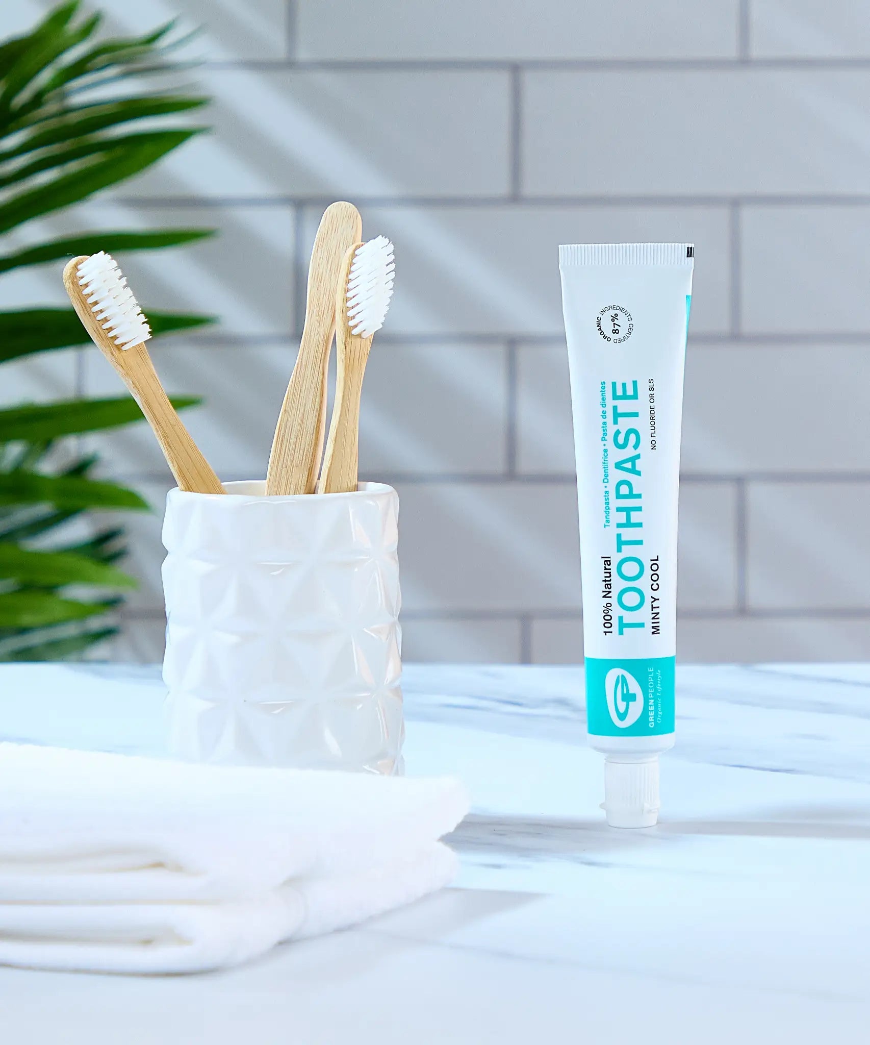 Organic People minty cool toothpaste tube in the bathroom next to a toothbrush holder 