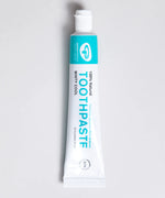 White and green branded tube of Green People minty cool toothpaste