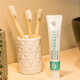 Tube of Organic People minty cool toothpaste next to a toothbrush holder