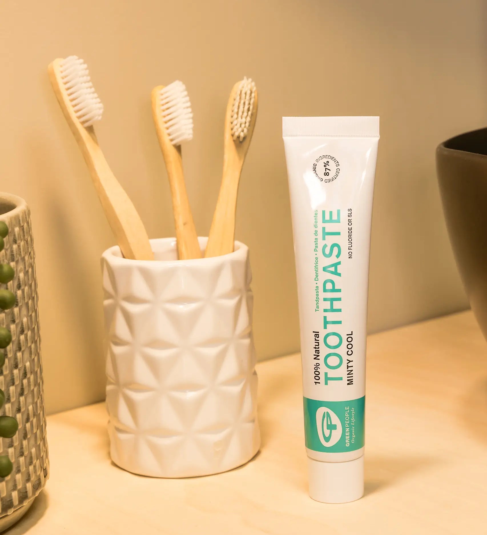 Tube of Organic People minty cool toothpaste next to a toothbrush holder