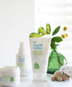 Organic Babies Baby Wash & Shampoo Scent Free placed on a white surface next to a wooden toy mouse. Other products from the organic babies collection can be seen in the background. 