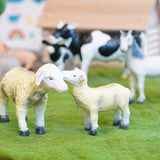 Green rubber toys sustainable sheep figures stood on some green felt in front of a horse and cow toy
