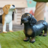 Green rubber toys dachshund and beagle stood on some green felt in front of a wooden toy tree