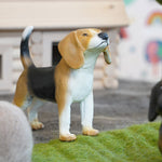 Green rubber toys eco-friendly beagle figure stood on some green felt in front of a small wooden house toy