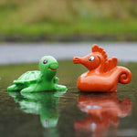 green turtle and orange red seahorse from the Green Rubber Toys Sea Friends Bath Toy Set pictured in a puddle of water outdoors