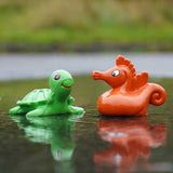 green turtle and orange red seahorse from the Green Rubber Toys Sea Friends Bath Toy Set pictured in a puddle of water outdoors