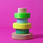 two of the children are holding Grimm's Small Conical Stacking Tower in Neon Green.