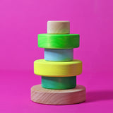 two of the children are holding Grimm's Small Conical Stacking Tower in Neon Green.
