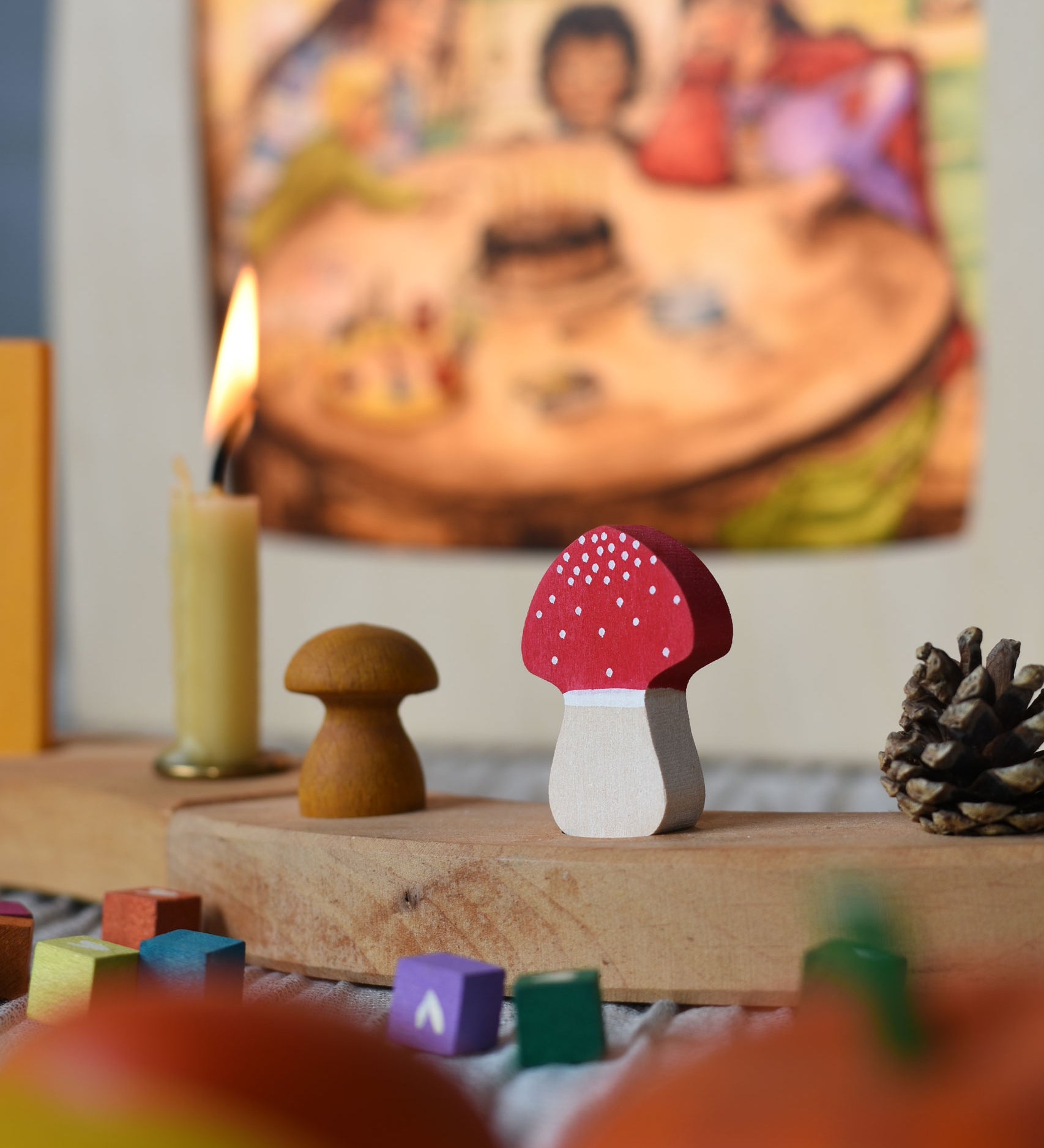 A Grimm's fly agaric red and white mushroom decorative figure placed on a natural celebration ring. A Toverlux lamp can be seen in the background.