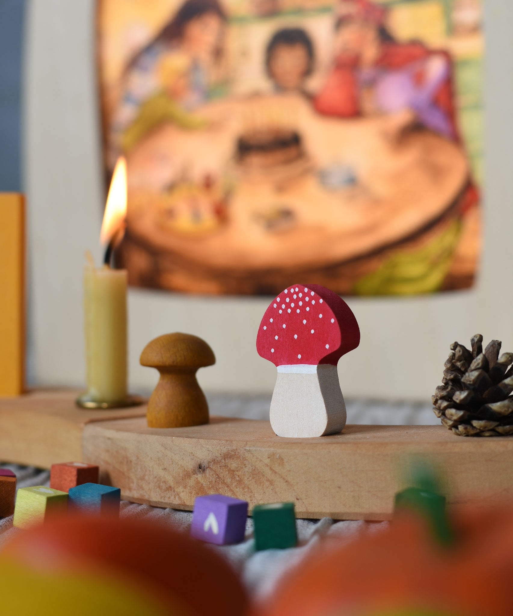 A Grimm's fly agaric red and white mushroom decorative figure placed on a natural celebration ring. A Toverlux lamp can be seen in the background.